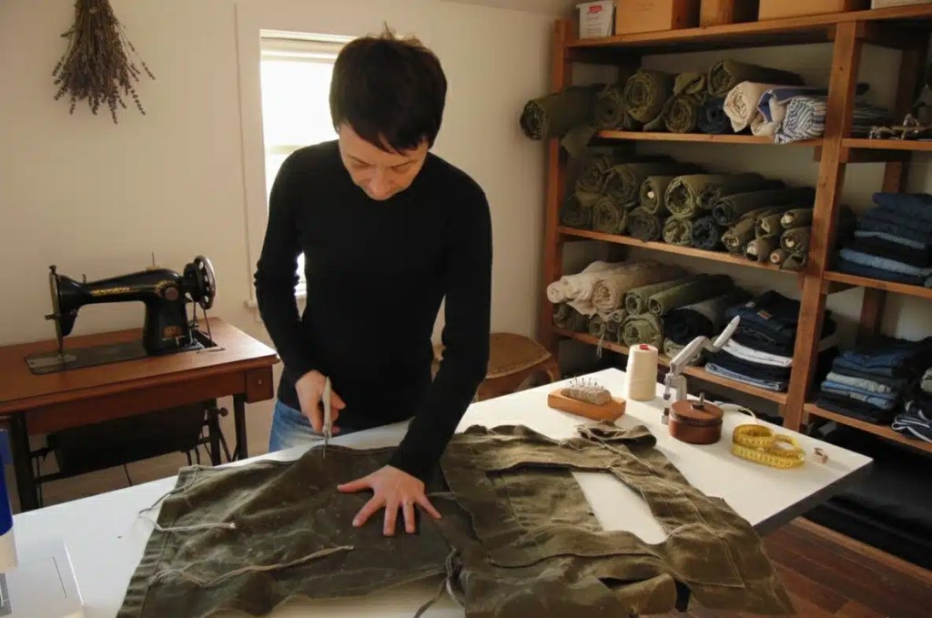 Vanessa Pointeau créatrice artisanale en Bretagne découpant une toile militaire dans son atelier de maroquinerie.
