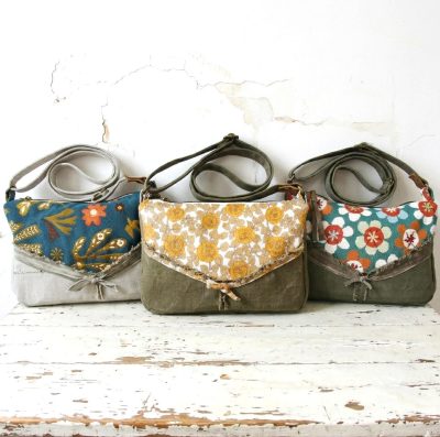 Trois sacoches bandoulière upcyclées en lin jaune, jacquard bleu et fleuri sur une table en bois vintage, mode éthique